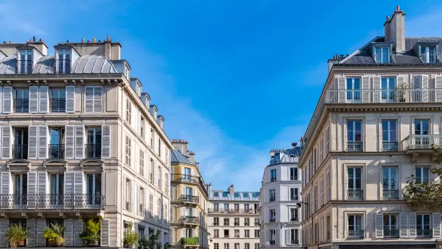 Traditional Paris apartment buildings lining a residential street under a clear blue sky