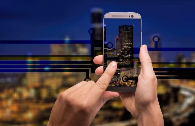 A hand holding a mobile phone connecting to smart city